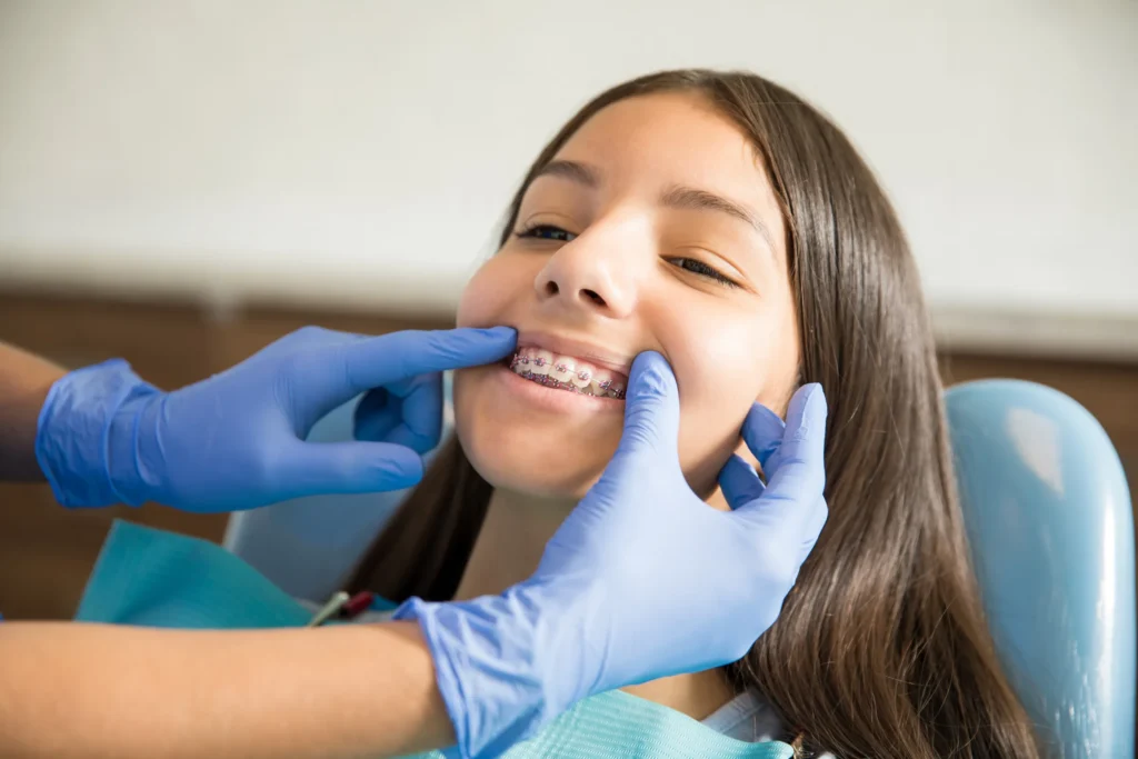 Dentist checking a smiling teenage girl's braces