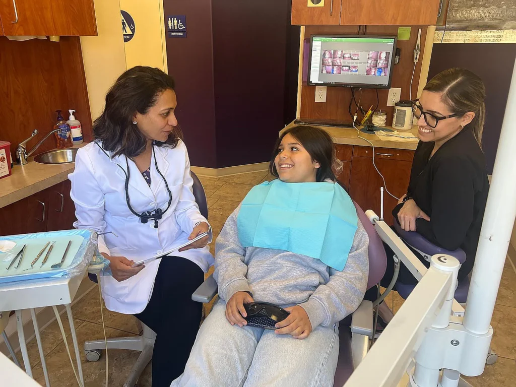 Dr. Kanak Trivedi talking with a patient in the dental chair while a team member looks on
