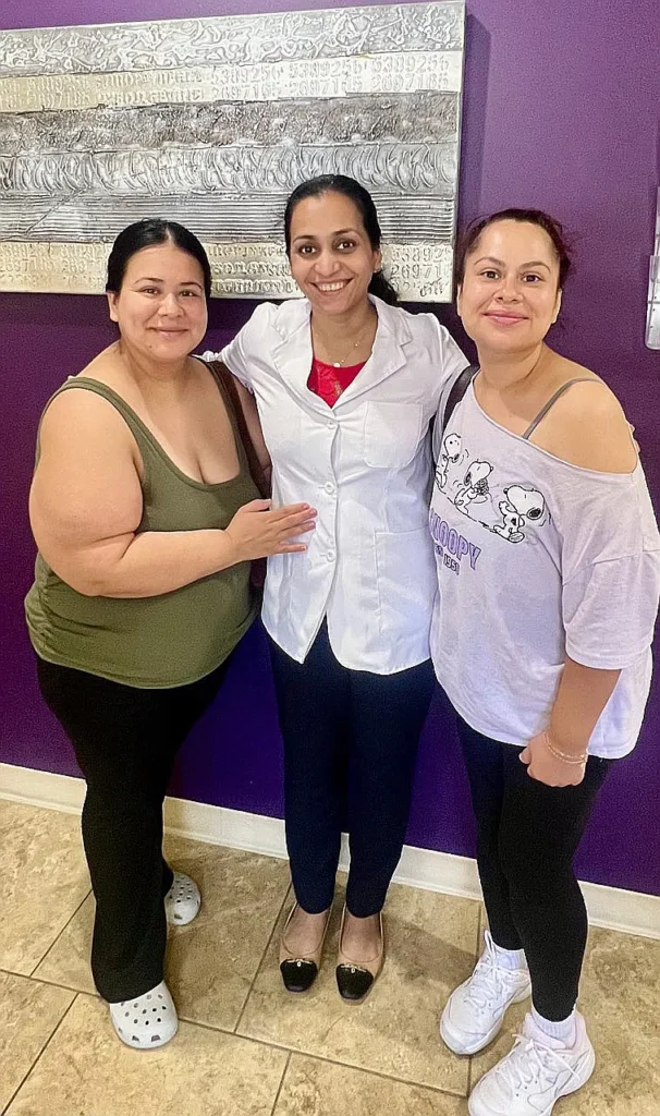 Dr. Kanak Trivedi with two patients in front of a purple wall