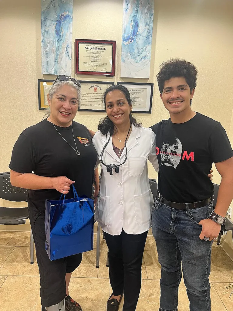 Dr. Kanak Trivedi with two patients in front of her framed diplomas