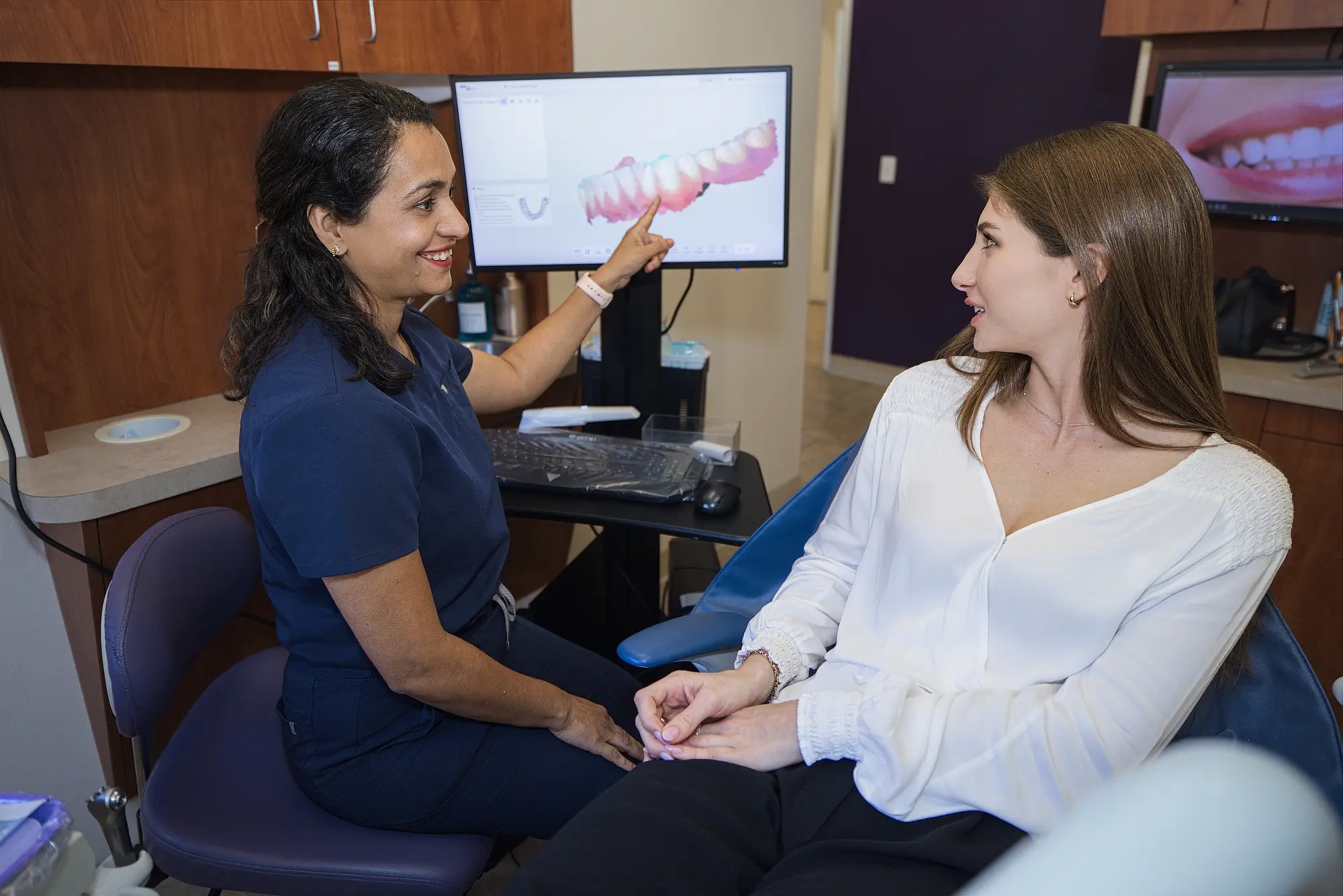 Dr. Trivedi showing a patient a 3D scan of her teeth on a monitor